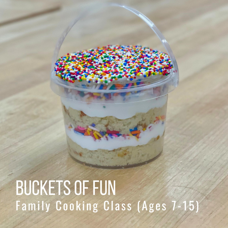 Cupcake in a plastic bucket with sprinkles, wood table.
