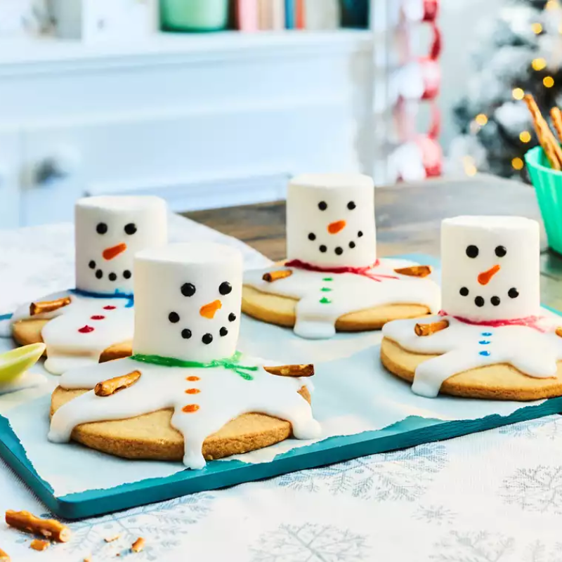 Snowman cookies with marshmallow heads and icing bodies on a tray.