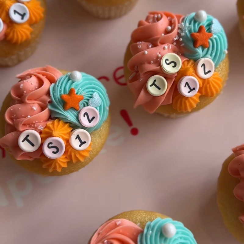 Cupcakes with pink, blue frosting, star sprinkles, and 'TS 12' decorations.