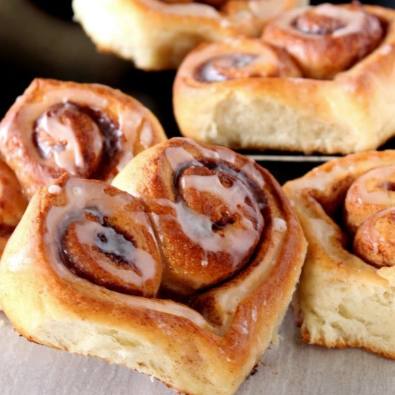 Close-up of glazed cinnamon rolls on a baking sheet.