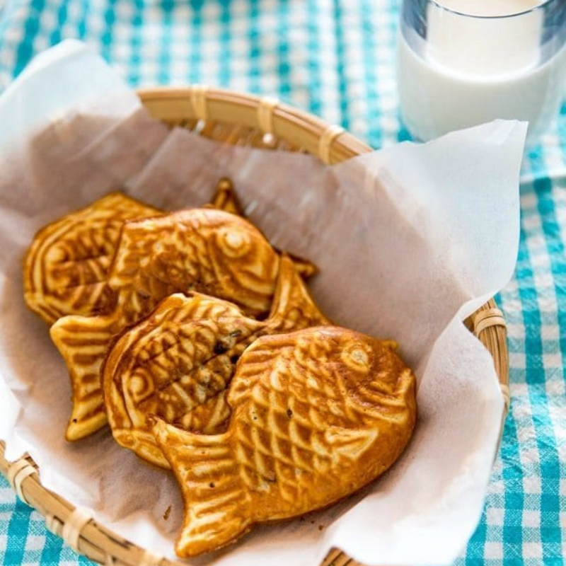 Fish-shaped pastries in a basket on a checkered tablecloth.
