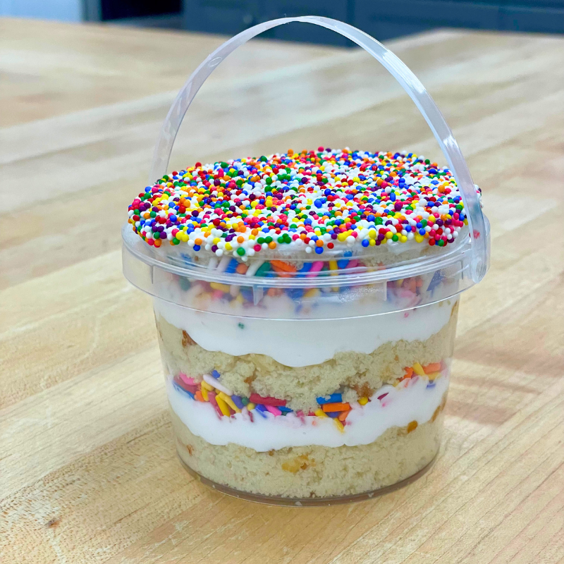 Cupcake in a plastic cup with sprinkles on top.