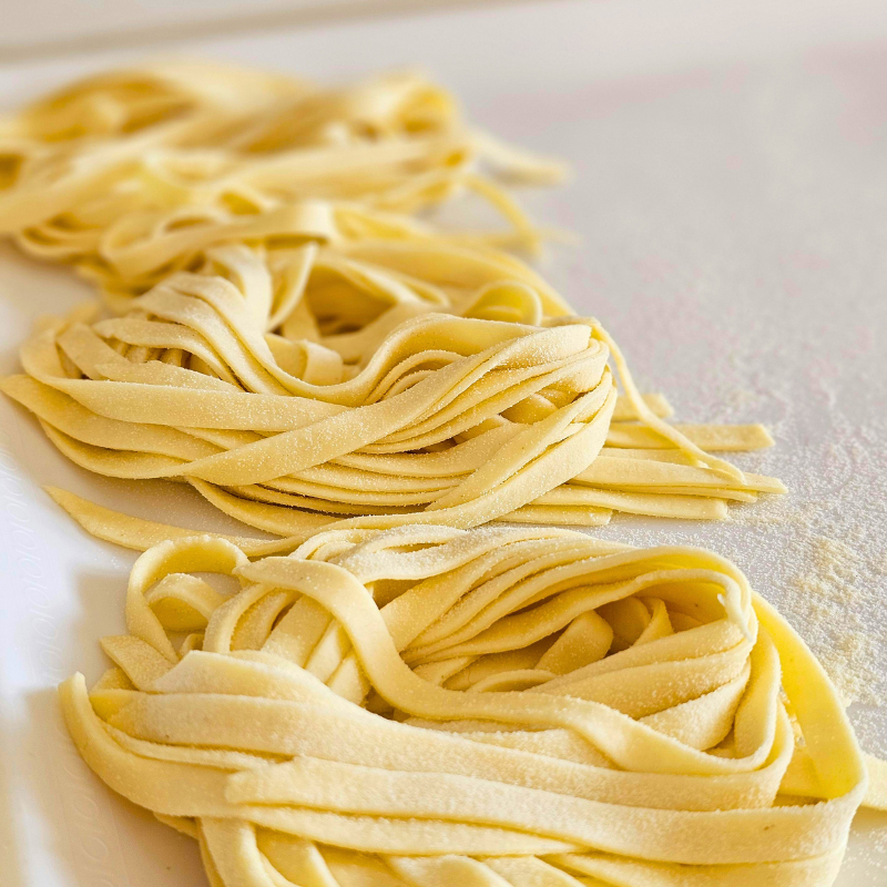 Freshly made pasta noodles arranged on a floured surface.