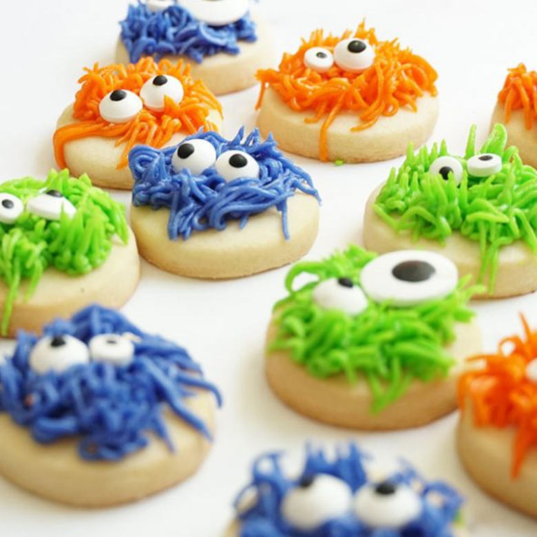 Cookies decorated with colorful icing and googly eyes, resembling monsters.