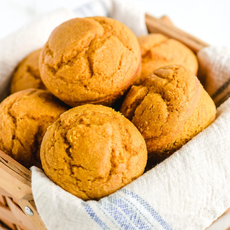 Basket of golden-brown muffins in a cloth-lined basket.