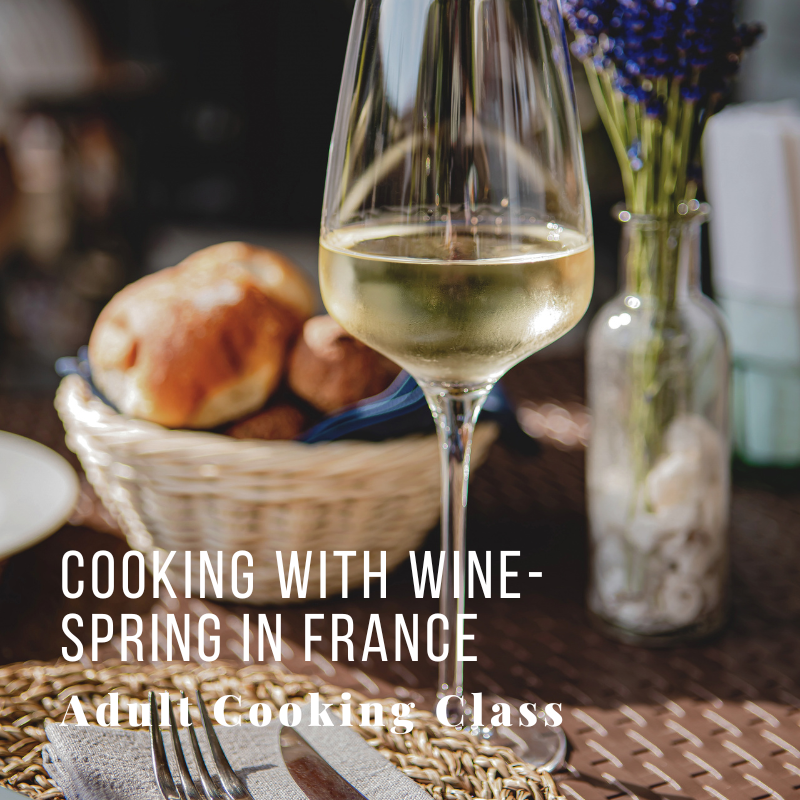 Glass of white wine on a table with bread and lavender in the background.
