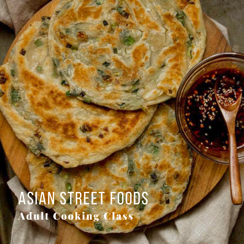 Three onion pancakes on a wooden plate with a bowl of dipping sauce.