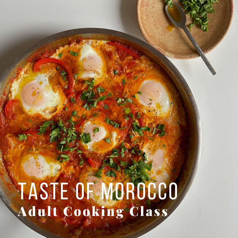 Pan of Moroccan shakshuka with eggs, herbs, and spices on white background with text overlay.