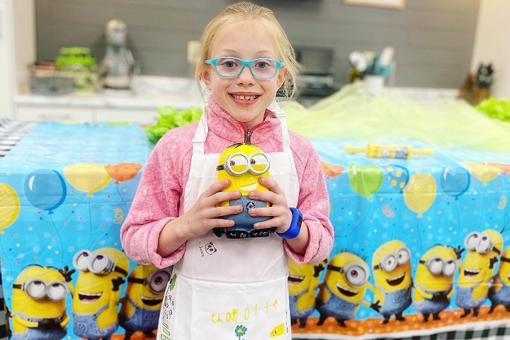 a little girl standing in front of a cake