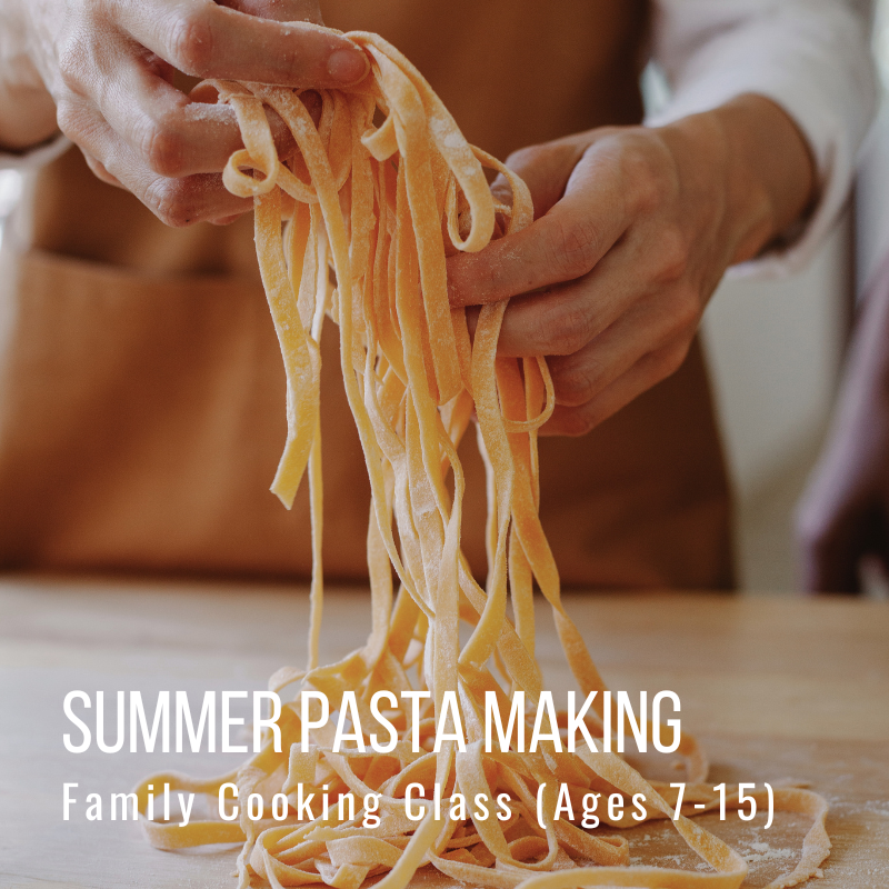 Person holding freshly made pasta strands over a wooden table.
