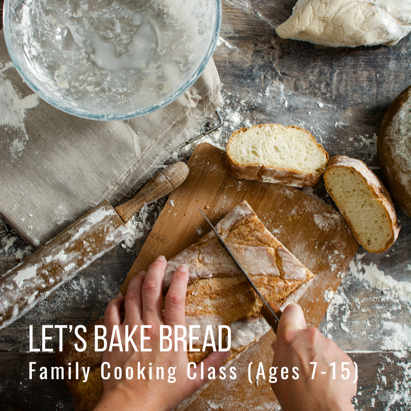 Hands slicing bread on a wooden table with flour and baking tools.