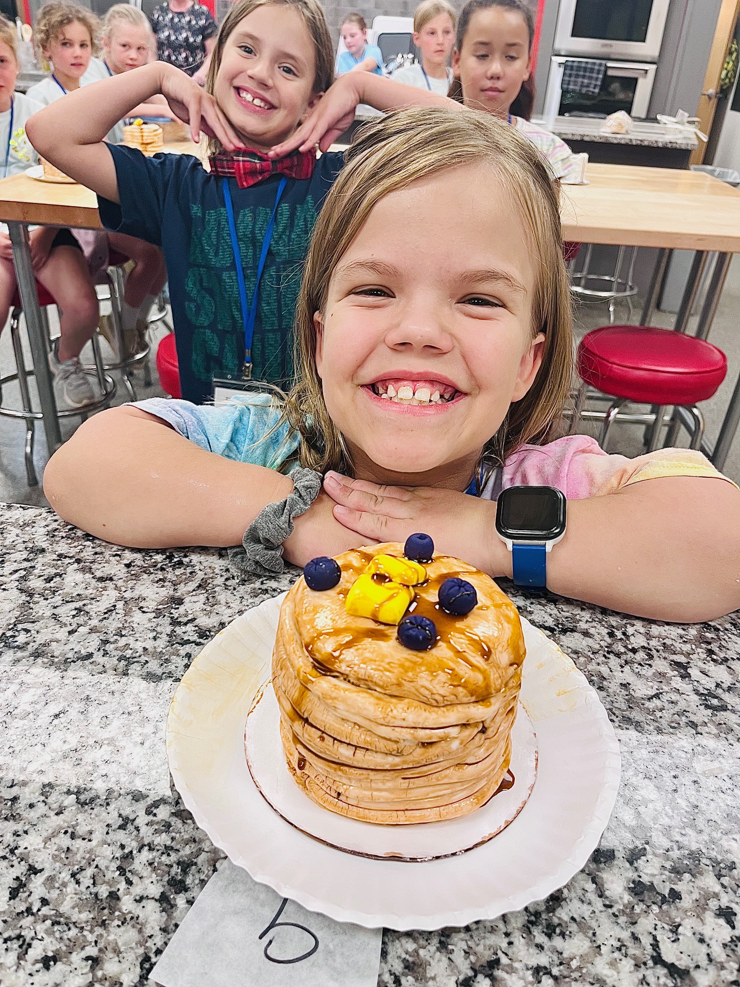 a little girl sitting at a table with a cake on a plate