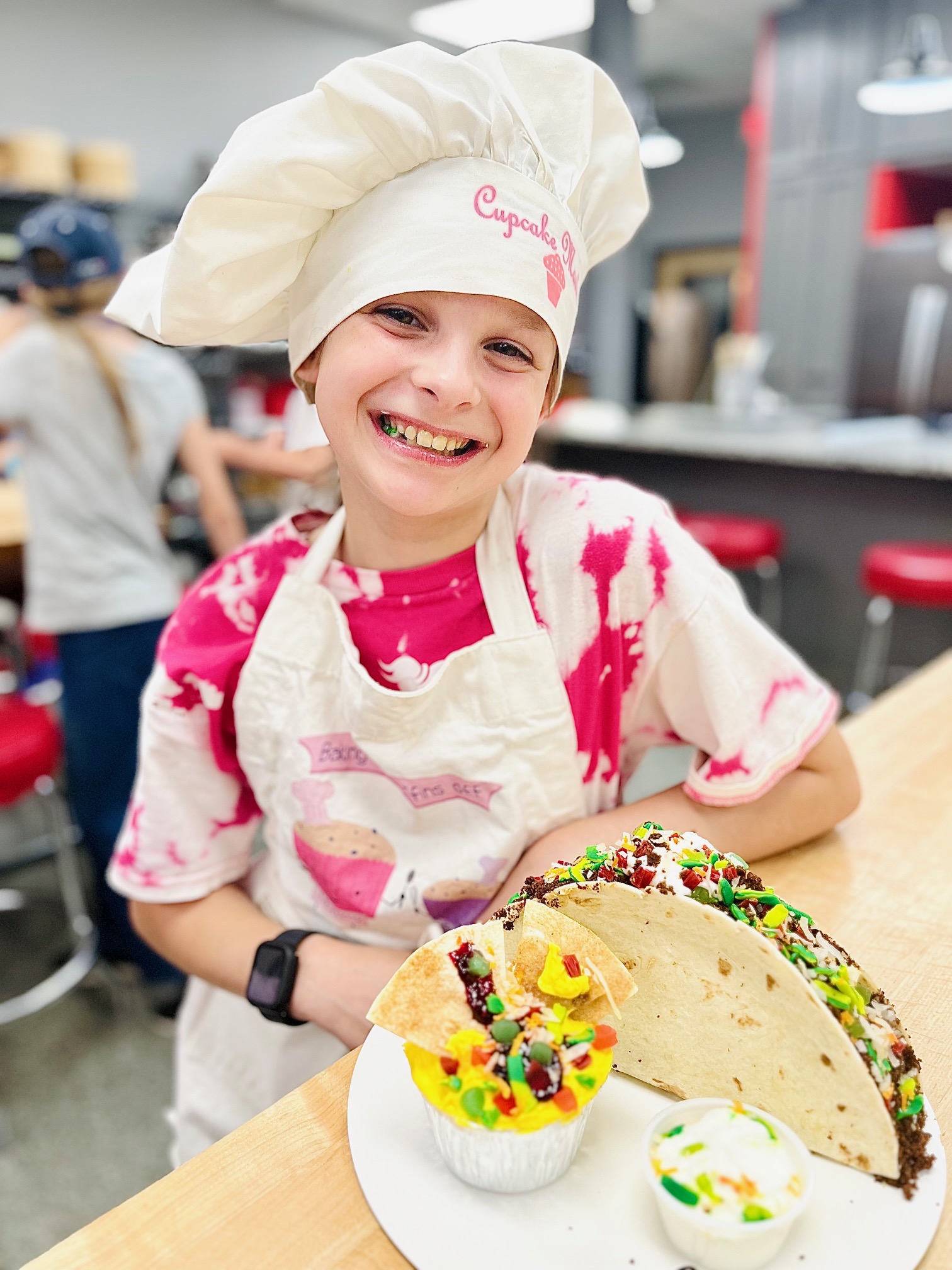 a little girl holding a piece of cake on a table
