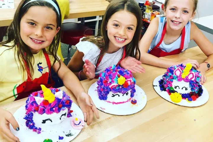 a little girl sitting at a table with a birthday cake
