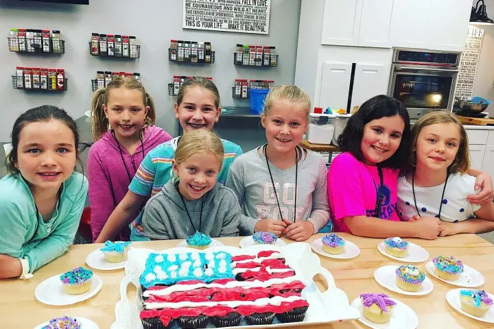 a group of people sitting at a table with a birthday cake