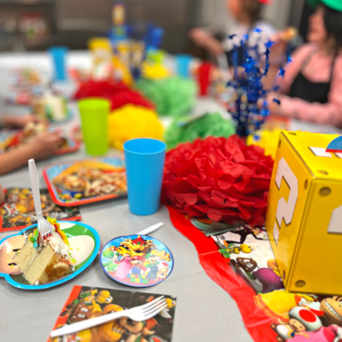 a group of people sitting at a table with a birthday cake