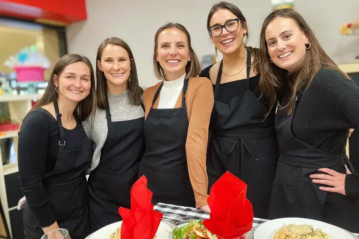 a group of people posing for a photo in front of a cake
