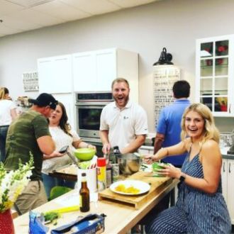 a group of people standing in a kitchen preparing food