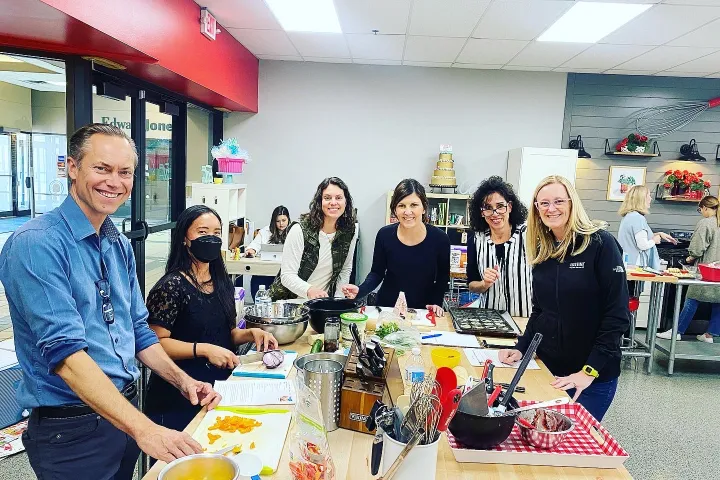 a group of people standing around a table with a cake