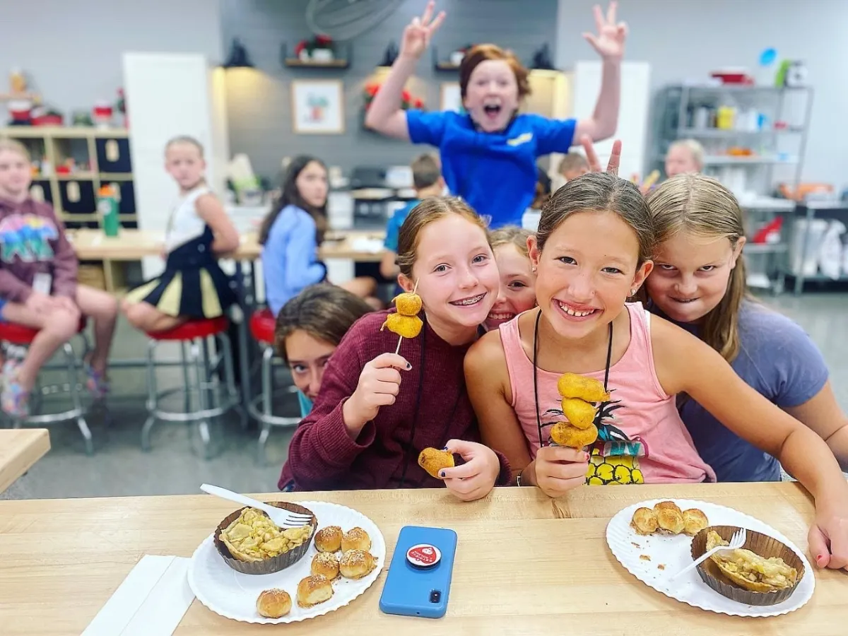 a little boy sitting at a table with a plate of food