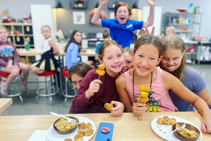a little boy sitting at a table with a plate of food