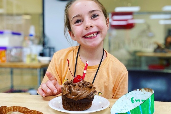 a woman sitting at a table with a cake on a plate