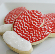 Decorated mitten-shaped cookies with red and white zigzag icing on a white plate.