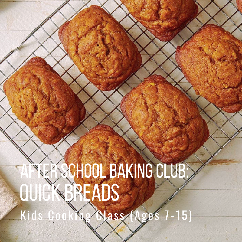 Five rectangular loaves of quick bread on a cooling rack.