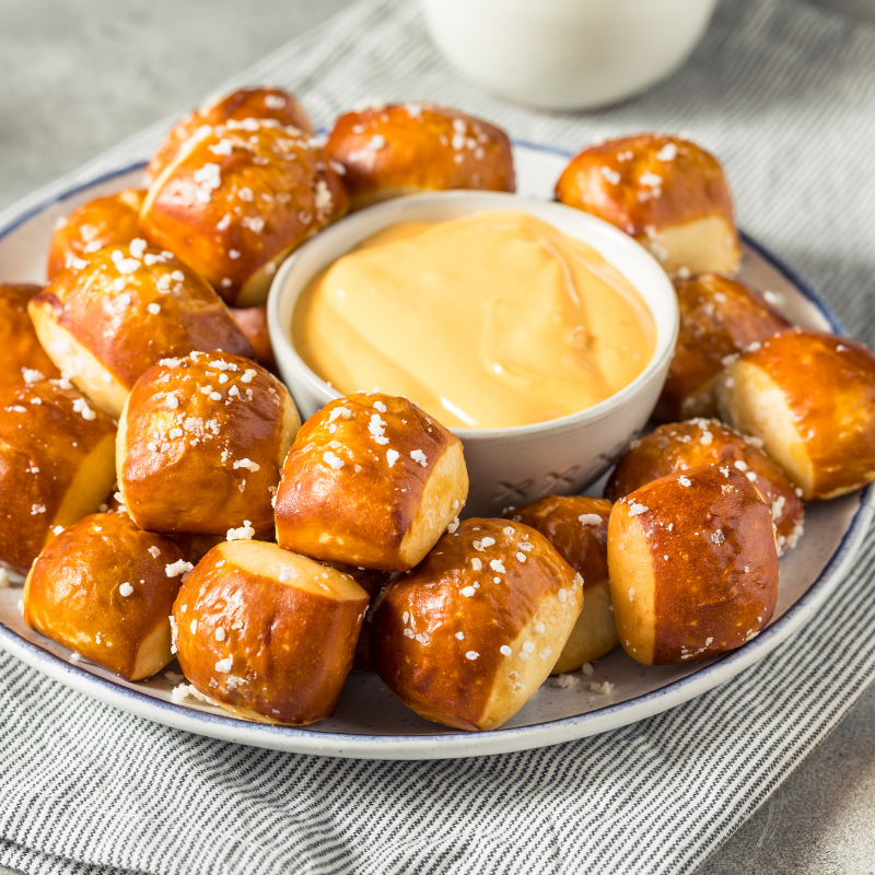 Plate of pretzel bites with cheese dip on a cloth napkin.