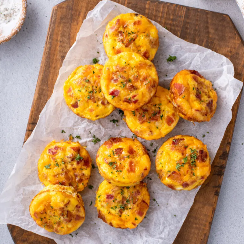 Mini quiches with bacon on parchment-lined board