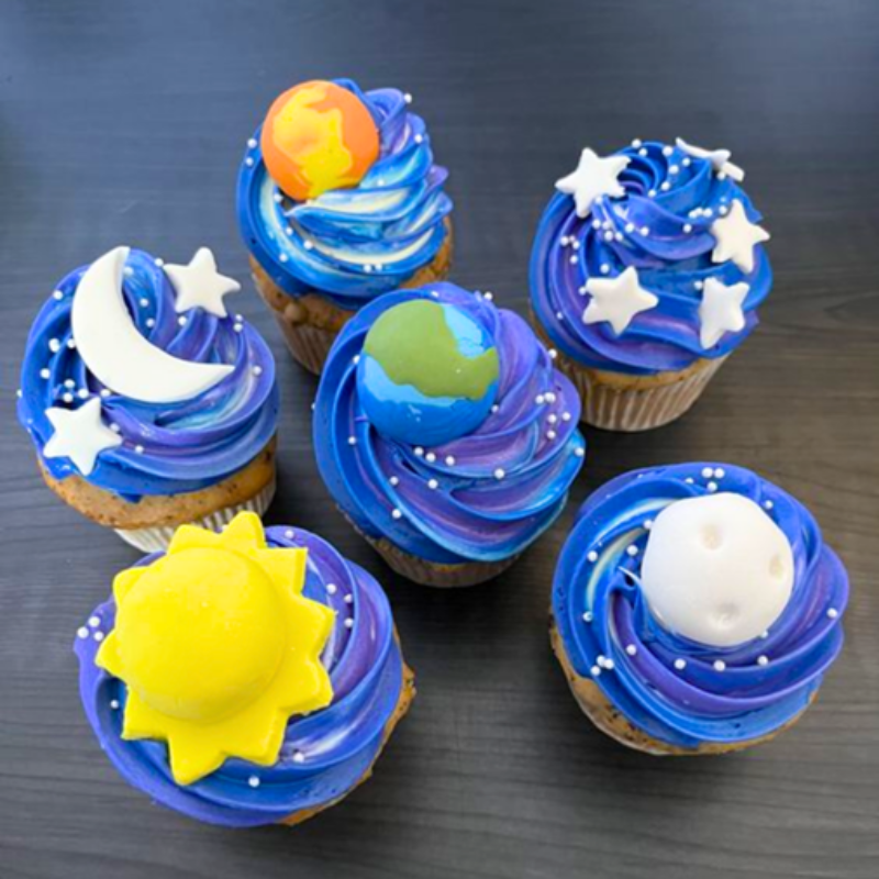 Cupcakes with space-themed decorations: planets, stars, sun, and moon.