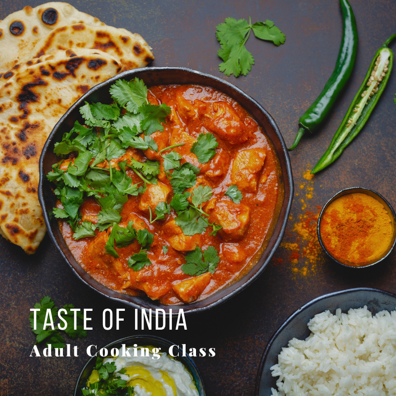 Indian curry dish with naan, rice, spices, and herbs on dark background.