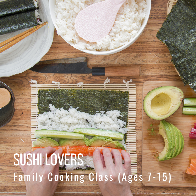 Hands rolling sushi, surrounded by ingredients on a wooden surface.