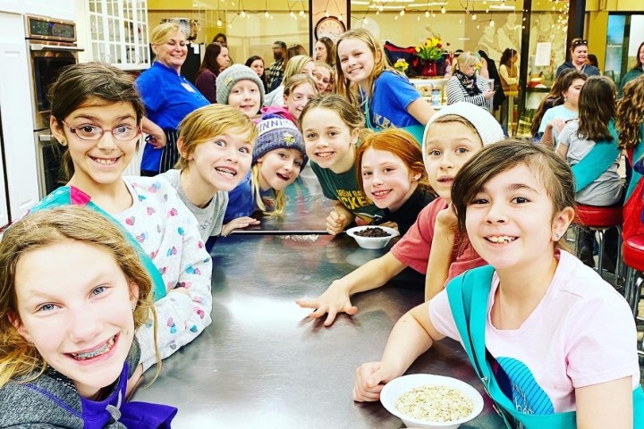 Group of children and adults smiling around a table in a bright room.