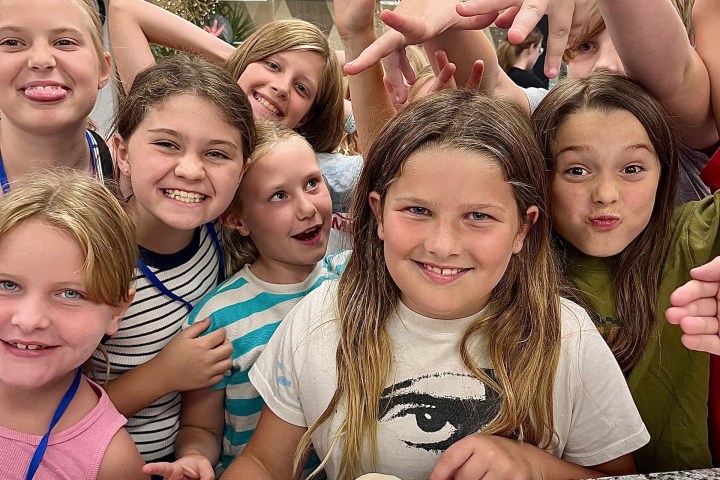 Group of children smiling and posing with plates of decorated pancakes.