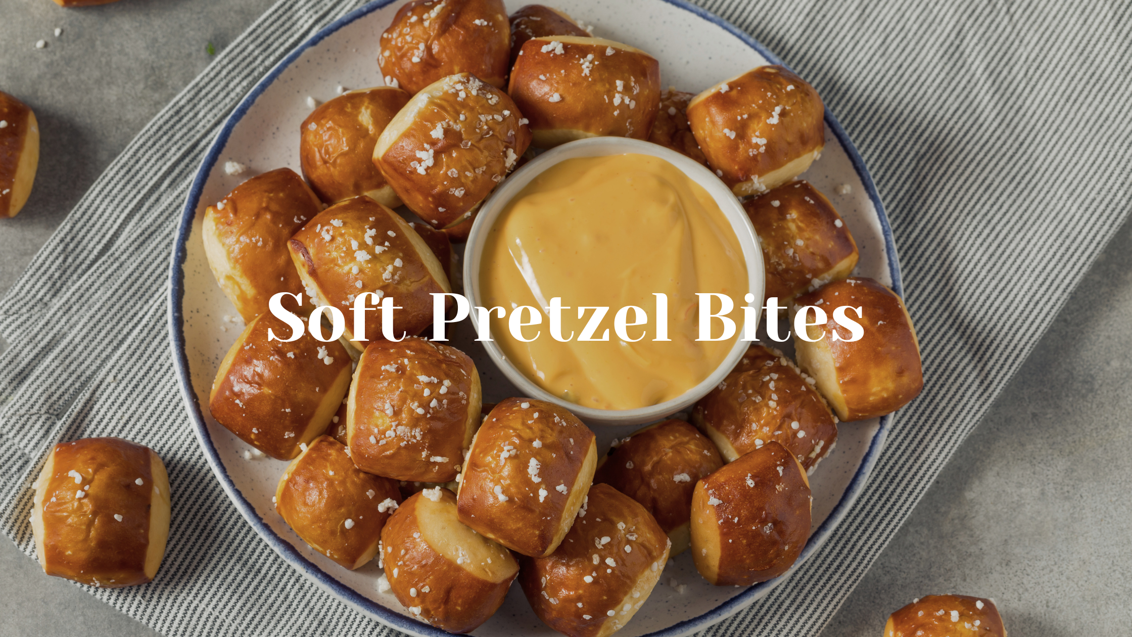 Bowl of pretzel bites with cheese dip on a striped cloth.